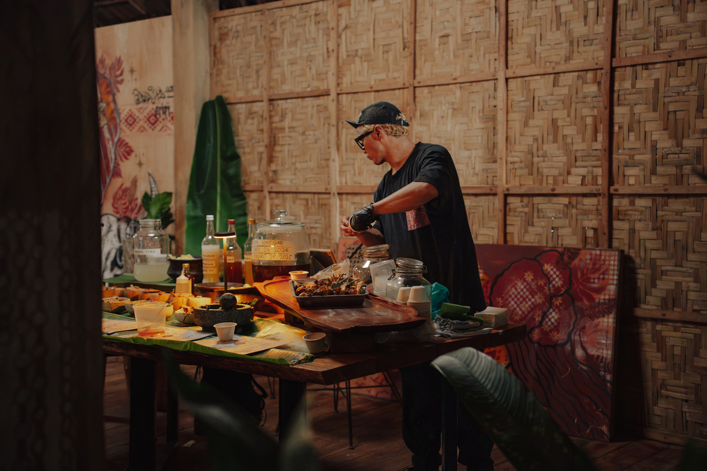 A cook plating food beside jars labelled vinegar