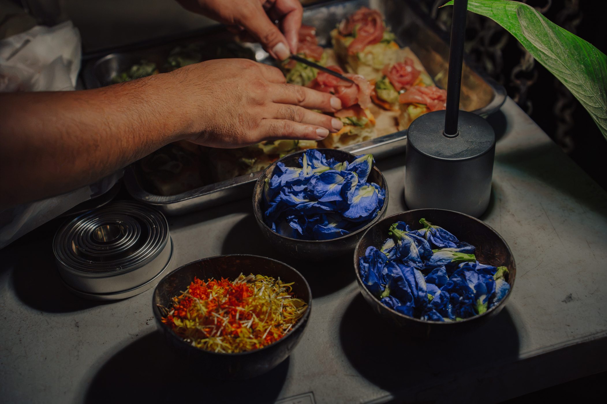 Hands plating flowers over a dish
